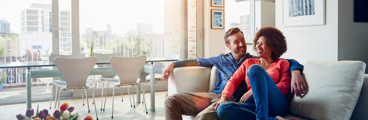 A male and female couple hanging out on the couch in their modern living room, enjoying the afternoon