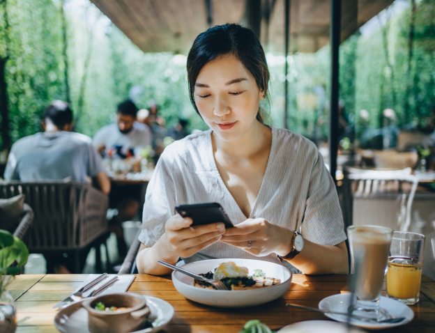 Woman at a table outside reading her phone